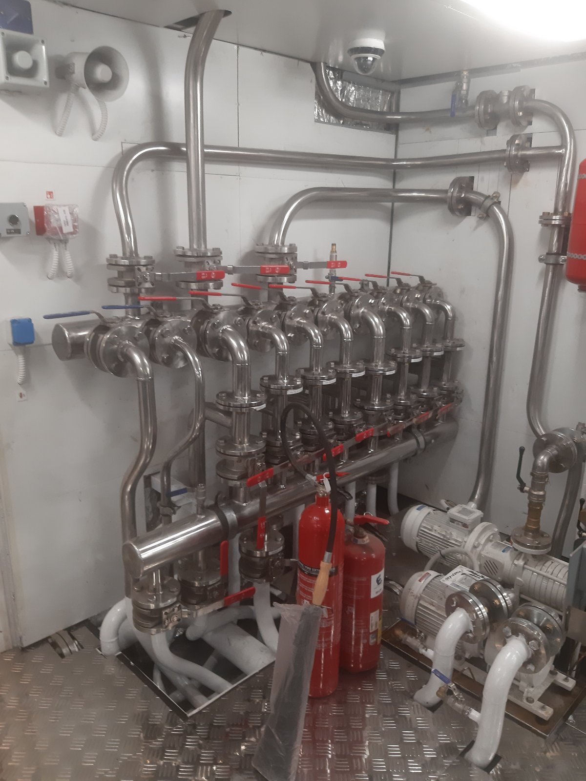 Completed stainless-steel piping manifold with valves and pump connections inside a vessel machinery space